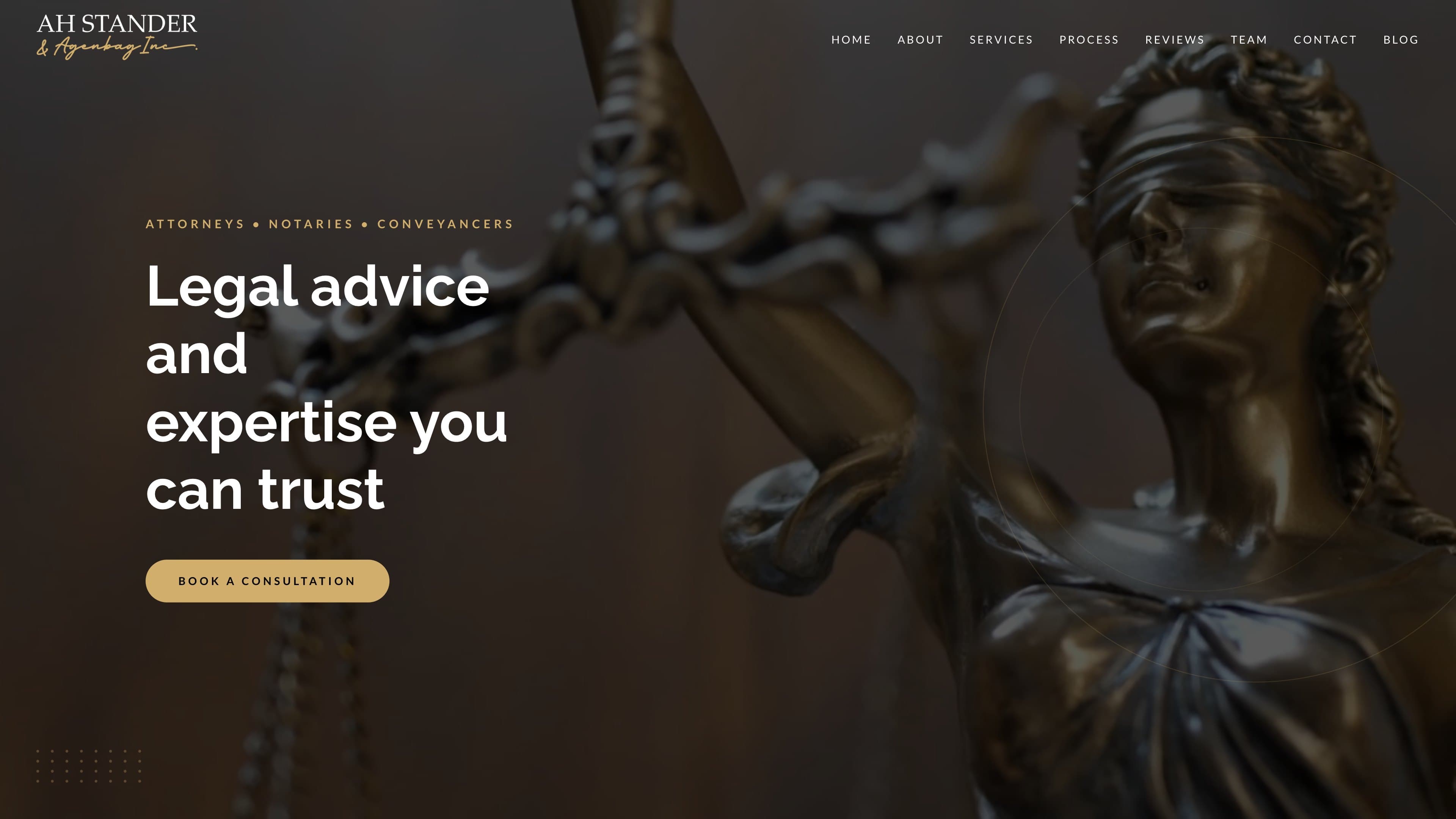 The AHS Law home page: a dark hero, gold book-a-consultation button, and a bronze statue of Justice